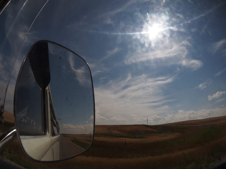 Rolling plain and big sky as seen out the passenger window, and in the mirror, of our bus Joy.